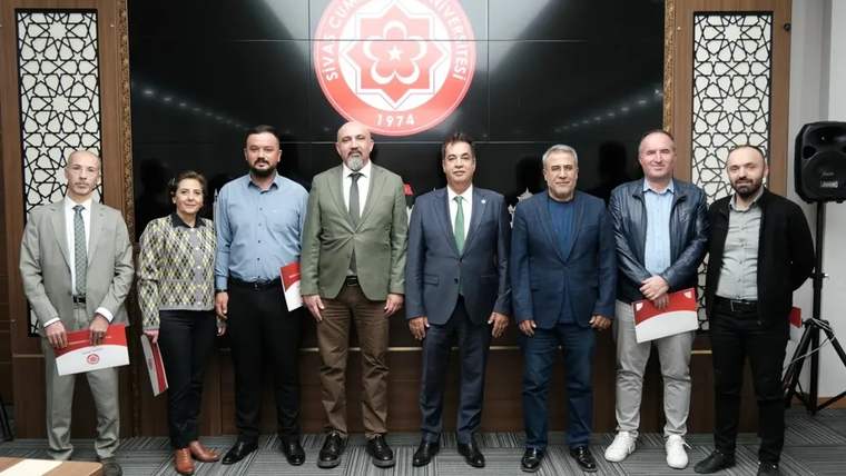 Sivas Cumhuriyet Üniversitesi'nin logosunun önünde, dokuz akademisyen bir arada duruyor.