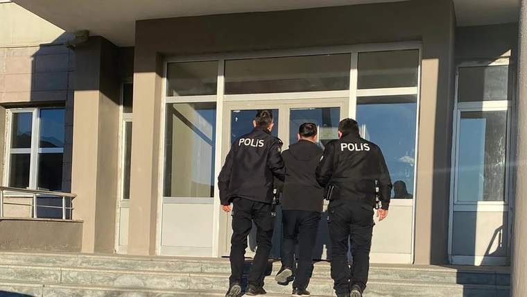 Üzerinde 'polis' yazılı kıyafetler giyen üç kişi, bir binanın girişine doğru yürüyor.