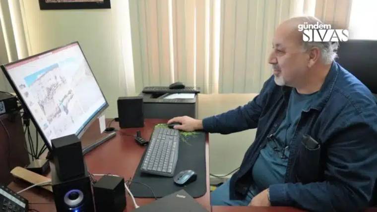Bilgisayar ekranına bakan bir kişi, ofis ortamında oturuyor.