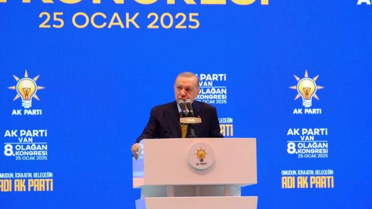 Mikrofon önünde konuşan bir kişi, üzerinde AK Parti ve Van 8. Olağan Kongresi yazılı mavi kürsüde duruyor.