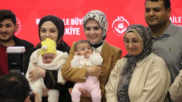 Farklı kadınlar ve bebekler, bir etkinlikte gülümseyerek poz veriyor.