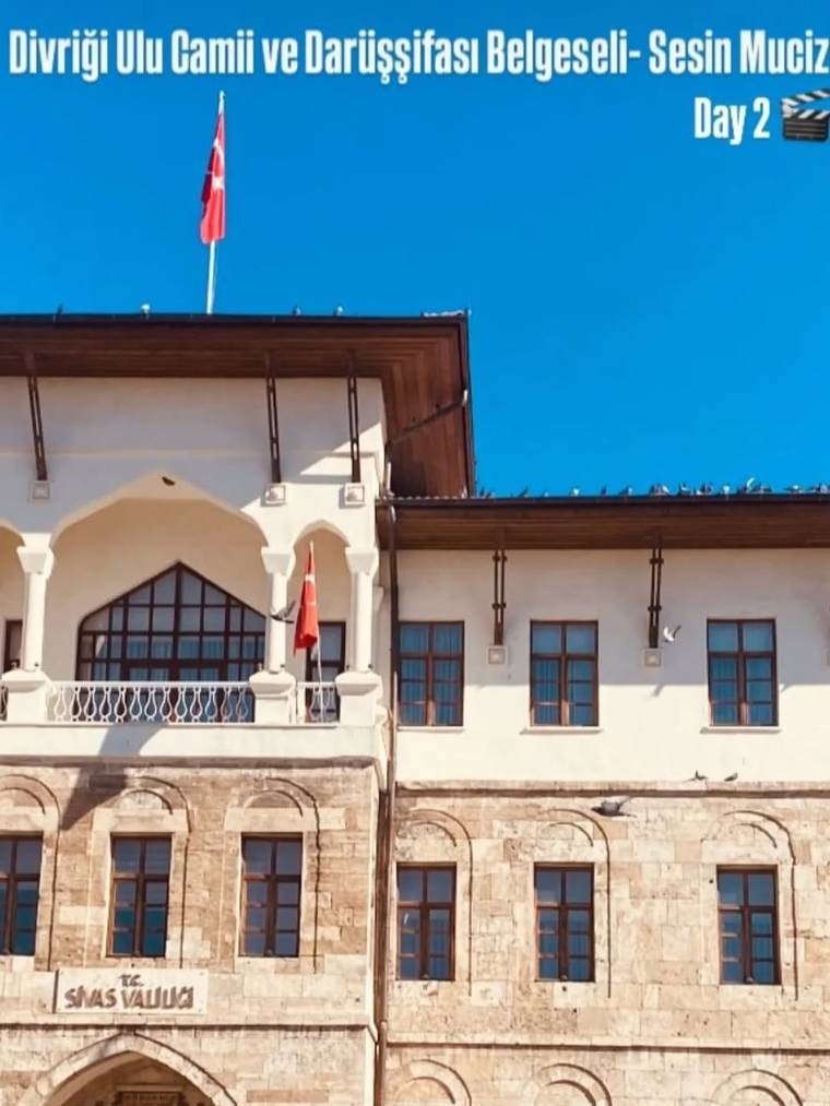 Üzerinde Sivas Valiliği yazan tarihi taş bina, balkonunda Türk bayraklarıyla mavi gökyüzü altında görülüyor.
