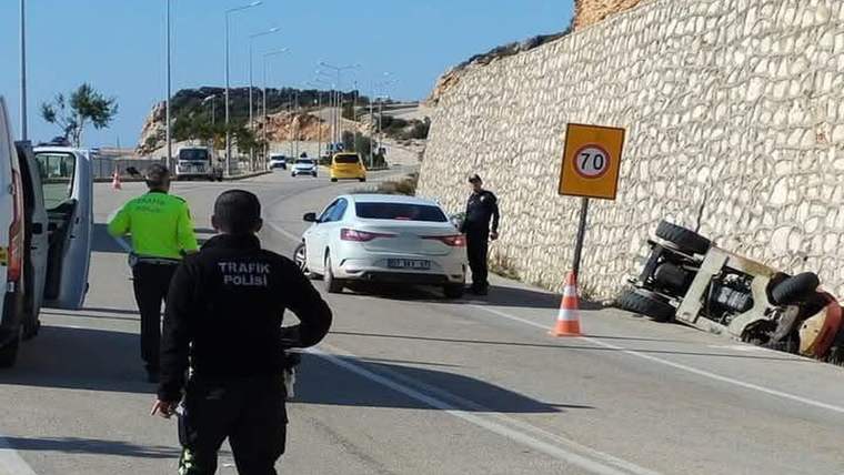 Yol kenarında devrilmiş forklift, trafik polisleri, bir otomobil ve 70 kilometre hız tabelası görülüyor.