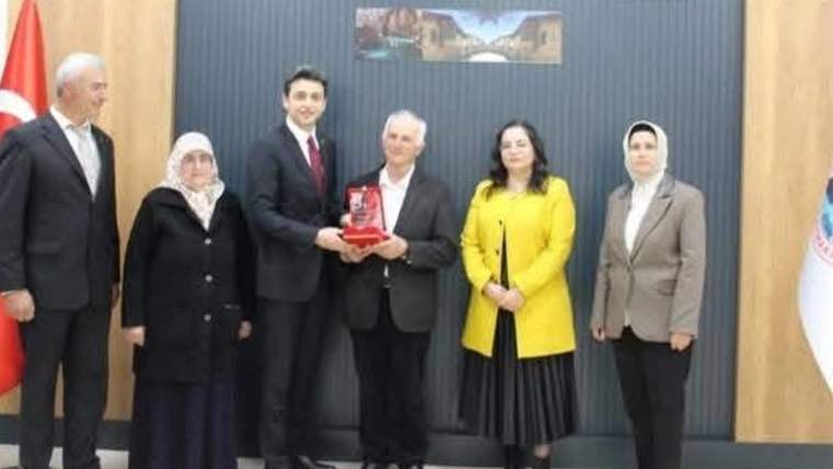 İbradı Kaymakamlığı yetkilisi, şehit ve gazilere plaket verirken, etrafında katılımcılar yer alıyor.