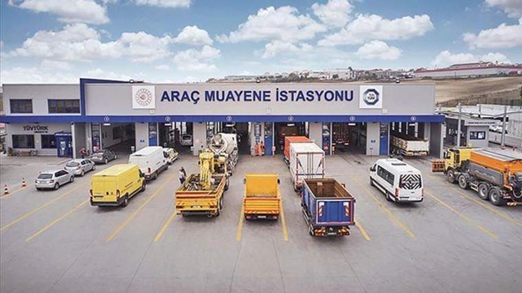 Araç muayene istasyonunun önünde çeşitli renklerde araçlar sıralanmış.