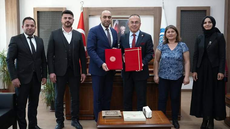 Bir odada altı kişi yan yana duruyor; ortadaki iki kişi kırmızı dosyalar tutarken arkada Türk bayrağı görülüyor.