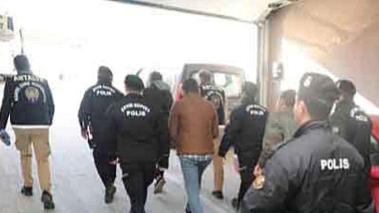 Üzerlerinde polis yazılı montlar bulunan görevliler, bir kişiyi bina içindeki koridorda götürüyor.