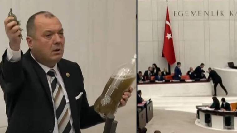 Bir kişi, elinde kirli su dolu bir şişe tutarak meclis salonunda konuşuyor.