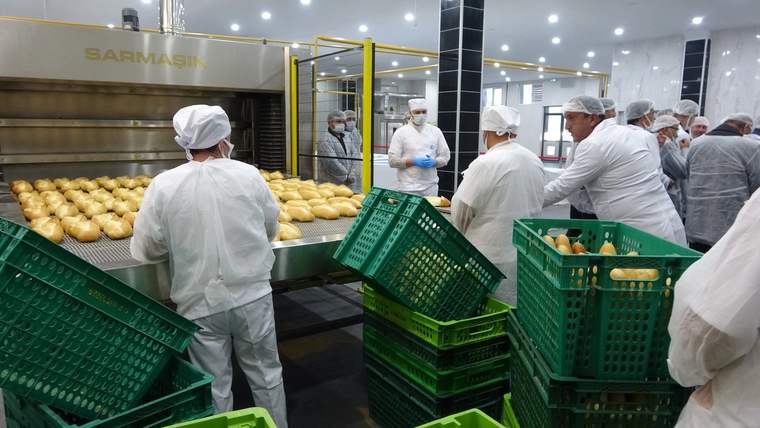 Yeni ekmek fabrikasında çalışanlar, ekmekleri sepetlere yerleştiriyor.