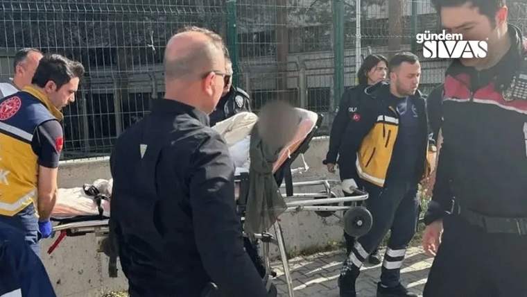 Ambulans sedyesinde bir kişi, etrafında sağlık ve güvenlik görevlileri var.