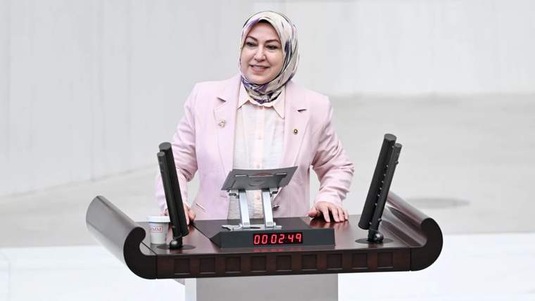 Kürsüde konuşan bir kadın, önünde bir mikrofon ve zamanlayıcı var.