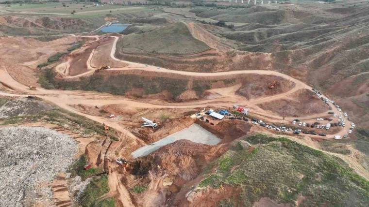 Havadan çekimde toprak yollarla çevrili şantiyede iş makineleri, araçlar ve birkaç çadır görülüyor.