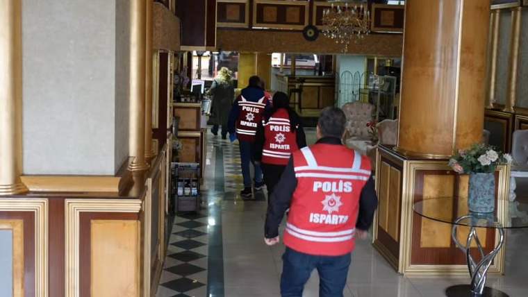 Üzerinde 'Polis' yazılı yelek giyen birkaç kişi, bir otelin lobisinde yürüyor.