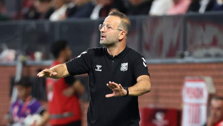 Saha kenarında siyah spor kıyafetli bir kişi iki elini öne uzatırken arka planda tribünler görülüyor.