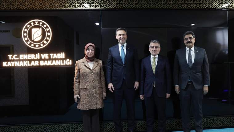 Enerji ve Tabii Kaynaklar Bakanlığı'nda dört kişi, arka planda bakanlık logosu ile birlikte poz veriyor.