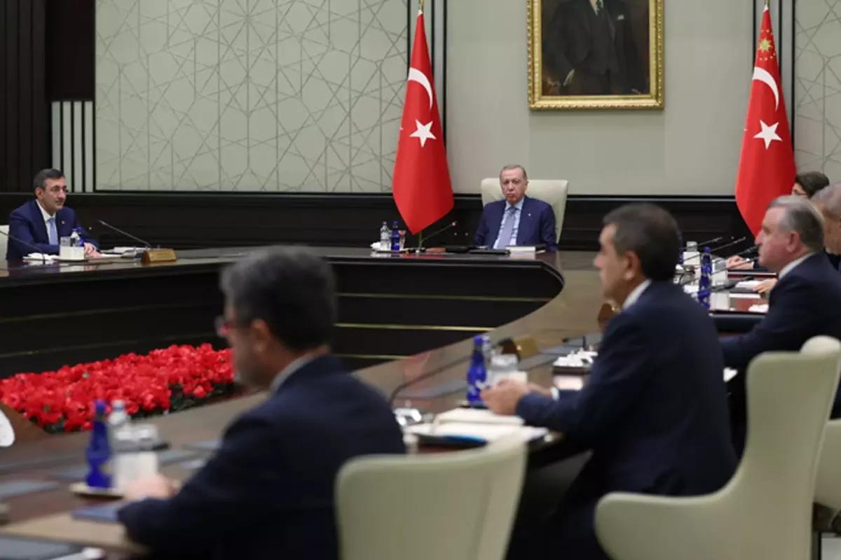 Bir toplantı odasında, masanın etrafında oturan beş kişi ve arka planda Türk bayrakları ile bir portre görünmekte.