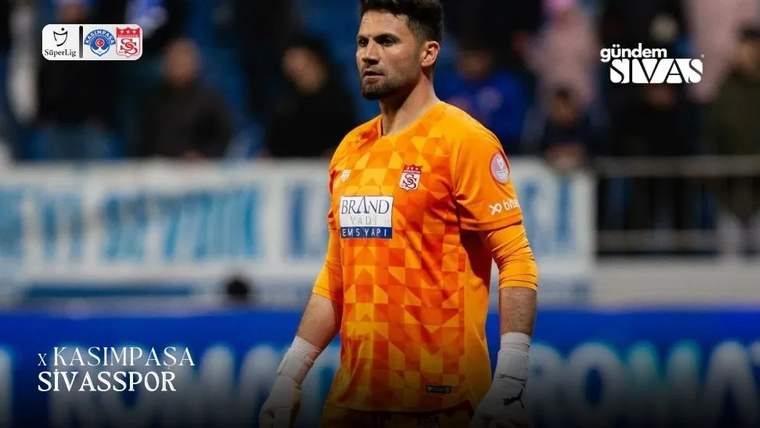 Sivasspor kalecisi, turuncu-kareli forma ile sahada duruyor.