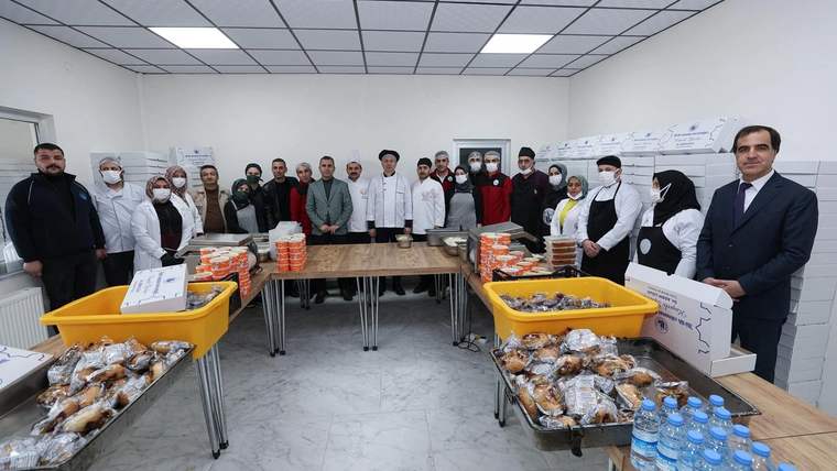 İftar yemeği hazırlayan ekip, yemeklerin bulunduğu masaların etrafında toplanmış.