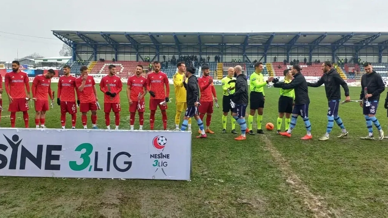 Düzcespor futbol takımı, kaleci ve hakemle birlikte sahada, zemin çamurlu.
