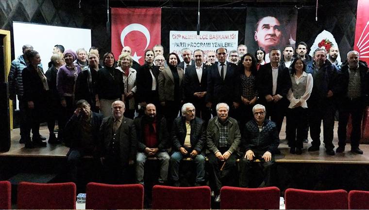 Sahnede Türk bayrağı ve pankart önünde, ayakta ve oturarak poz veren kalabalık grup