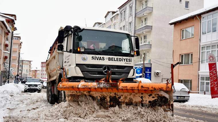 Üzerinde “Sivas Belediyesi” yazan kar küreme aracı, karlı ve çamurlu sokakta görülüyor.