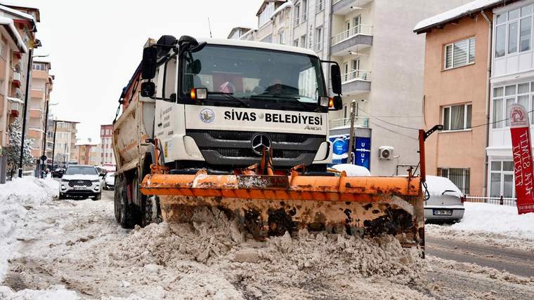 Üzerinde “Sivas Belediyesi” yazan kar küreme aracı, karlı ve çamurlu sokakta görülüyor.