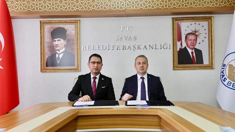 Sivas Belediyesi Başkanlığı'nda, iki kişi masada oturuyor ve belgeler imzalıyor.