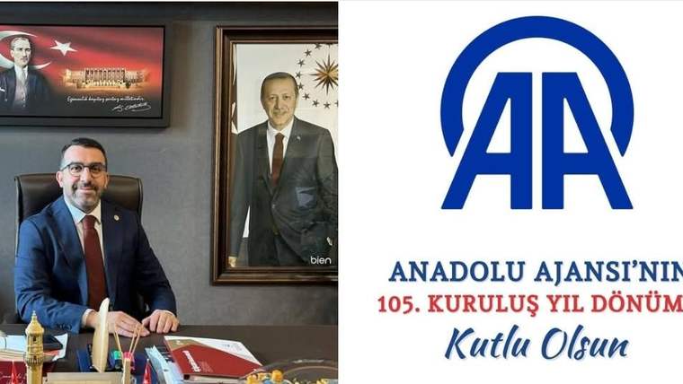 Masasında oturan bir kişi, yanında çerçeveli portre ve Anadolu Ajansı logosuyla birlikte görülüyor.