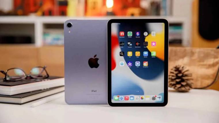 Masa üzerinde biri ekranı, diğeri arka yüzü görünen iki iPad; yanında kitaplar ve gözlük bulunuyor.