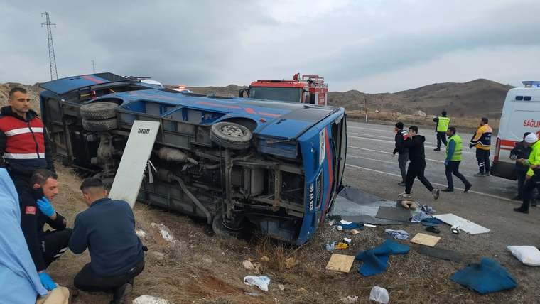 Devrilmiş mavi otobüsün çevresinde sağlık ve kurtarma ekipleri, yol kenarında yaralılarla ilgileniyor.