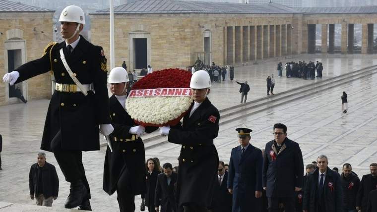 Askeri kıyafet giymiş üç kişi, Anıtkabir önünde çiçek buketi taşıyor.