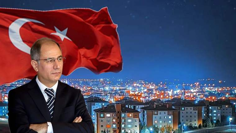 Arka planda Türk bayrağı ve gece manzarasıyla bir şehir, ön planda bir kişi duruyor.