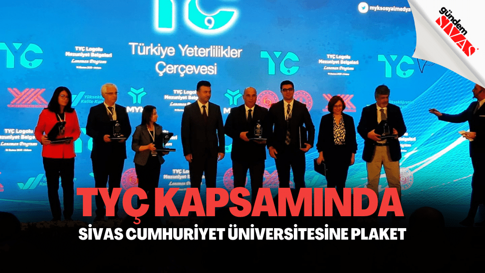 Plaket alan kişiler, arka planda TYÇ logosu ile birlikte sahnede duruyor.