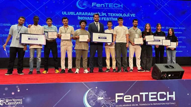 FenTech 2026 etkinliğinde ödül alan öğrenciler, sahnede sertifikalarıyla birlikte poz veriyor.