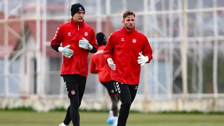 Kırmızı forma giymiş iki futbolcu, antrenman sahasında koşuyor.