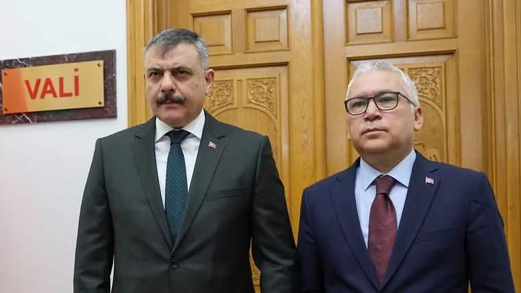 Sivas Valiliği önünde duran iki kişi, biri takım elbise giymekte.