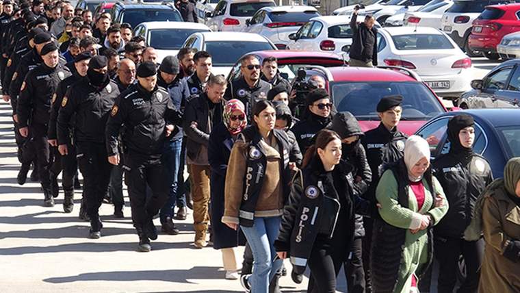 Otoparkta çok sayıda polis eşliğinde yürüyen kadın ve erkeklerden oluşan kalabalık görülüyor.