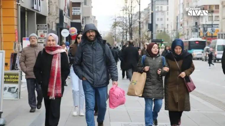 Kaldırımda yürüyen kalabalık, bazıları alışveriş poşetleri taşıyor.