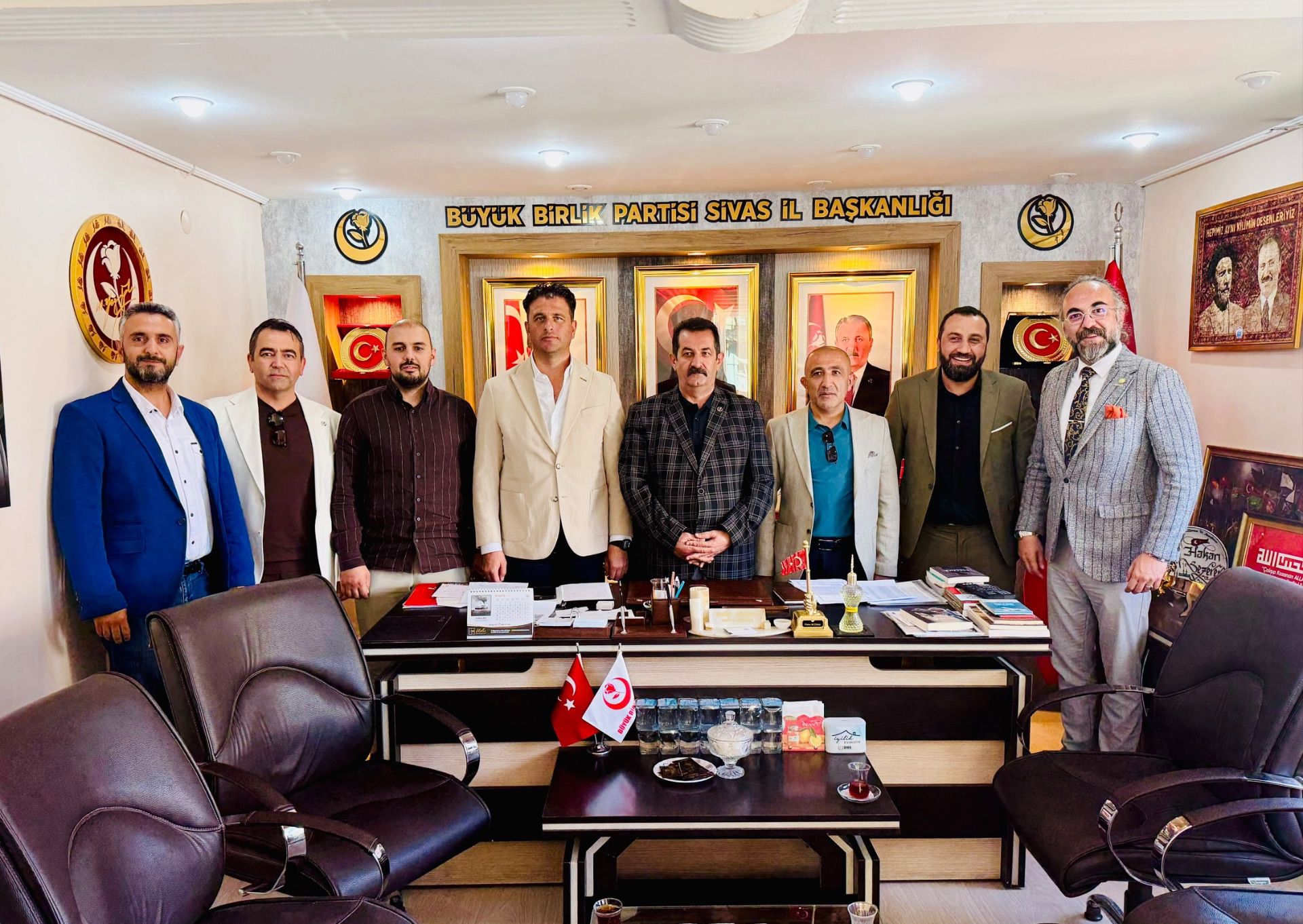 Üzerinde “Büyük Birlik Partisi Sivas İl Başkanlığı” yazan odada, masanın arkasında sekiz kişi duruyor.
