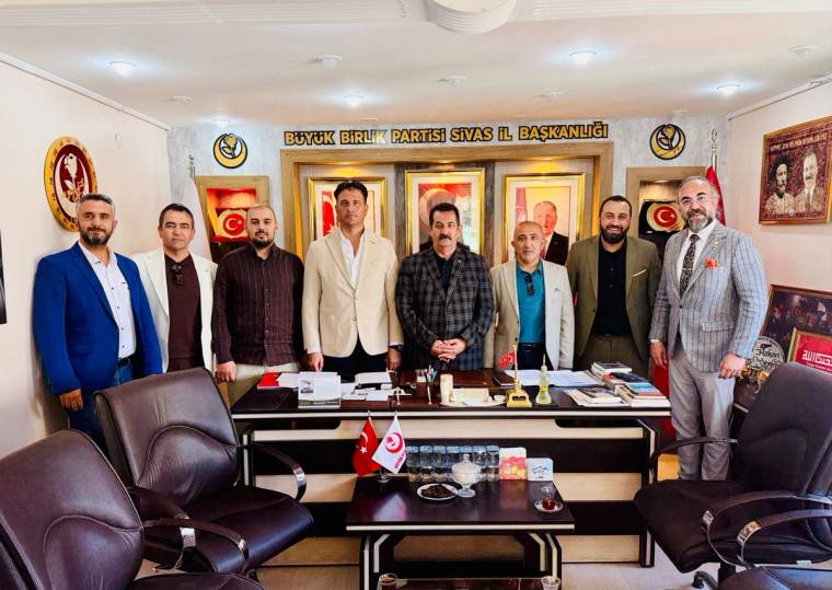 Üzerinde “Büyük Birlik Partisi Sivas İl Başkanlığı” yazan odada, masanın arkasında sekiz kişi duruyor.