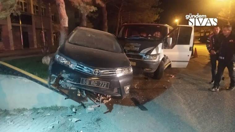 Gece bir sokakta önü hasarlı otomobil, arkasındaki beyaz araç ve sağda duran iki kişi görülüyor.