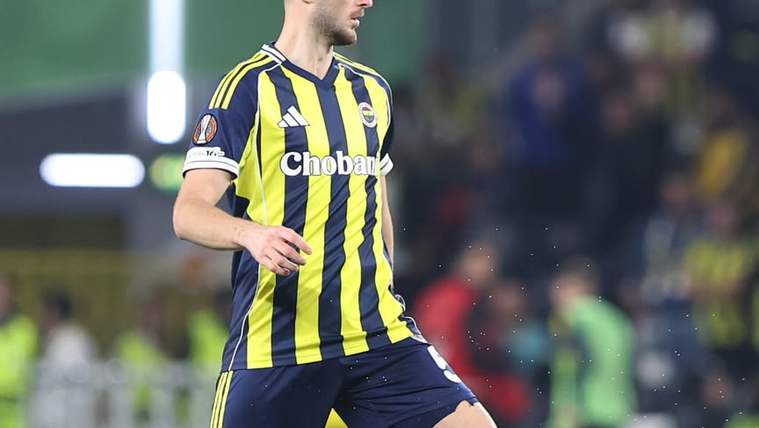 Sarı-lacivert çubuklu formalı futbolcu, sahada topa ayağıyla müdahale ederken görülüyor.