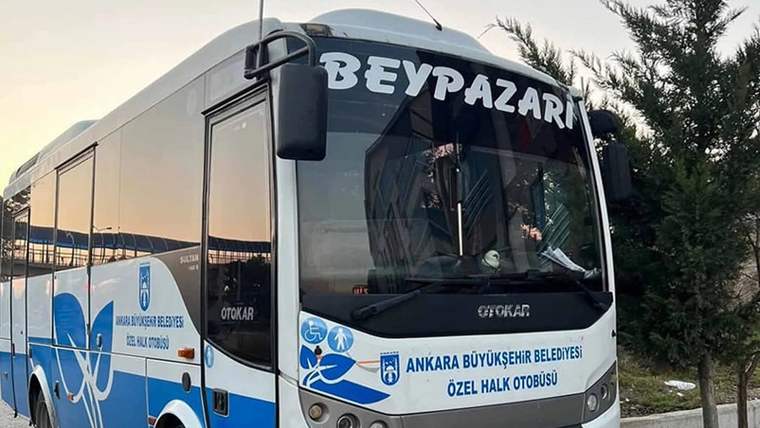 Üzerinde “Beypazarı” yazan mavi-beyaz özel halk otobüsü, yol kenarında ağaçların yanında duruyor.