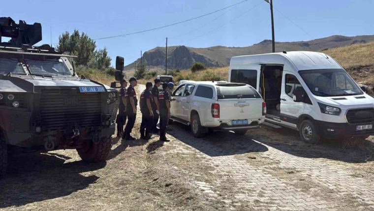 Dağlık arazide koyu renkli büyük araç, pikap ve minibüsün yanında üniformalı kişiler duruyor.