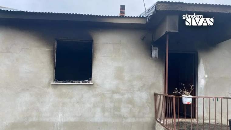 Dış cephesi islenmiş bir evin açık penceresi ve kapısı, balkon korkuluğunun arkasında görülüyor.