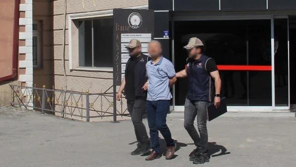 İki güvenlik görevlisi, bir kişiyi kolundan tutarak bir binanın önünde yürütüyor.