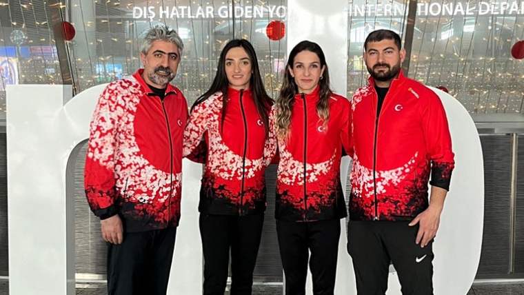Havalimanında, kırmızı-beyaz eşofmanlı iki kadın ve iki erkek yan yana poz veriyor.
