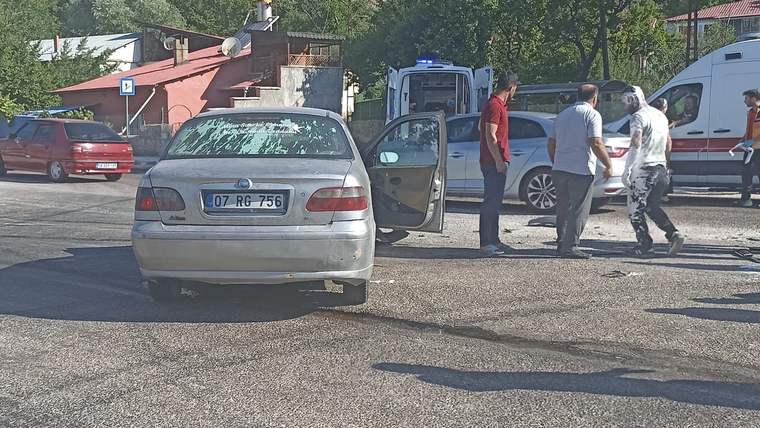 Yol kenarında duran gümüş otomobilin kapısı açık; çevresinde üç kişi ve bir minibüs görülüyor.