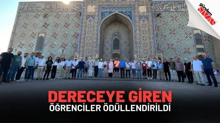 Çinilerle süslü kemerli bir yapının önünde, yan yana duran kalabalık bir grup görülüyor.