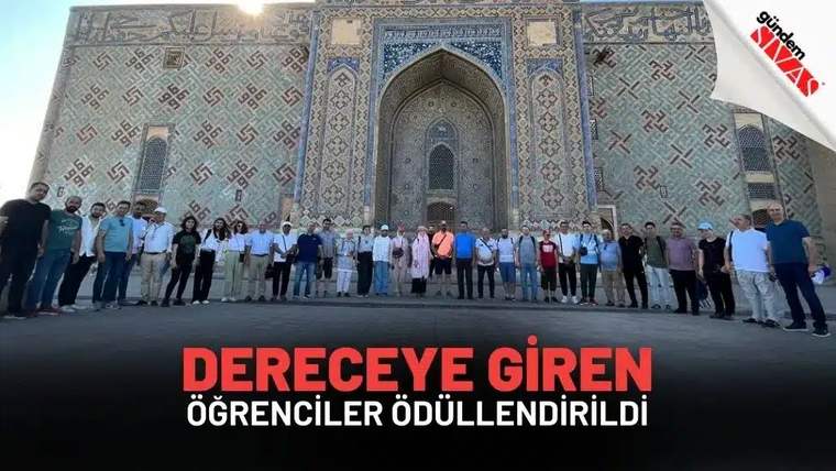 Çinilerle süslü kemerli bir yapının önünde, yan yana duran kalabalık bir grup görülüyor.
